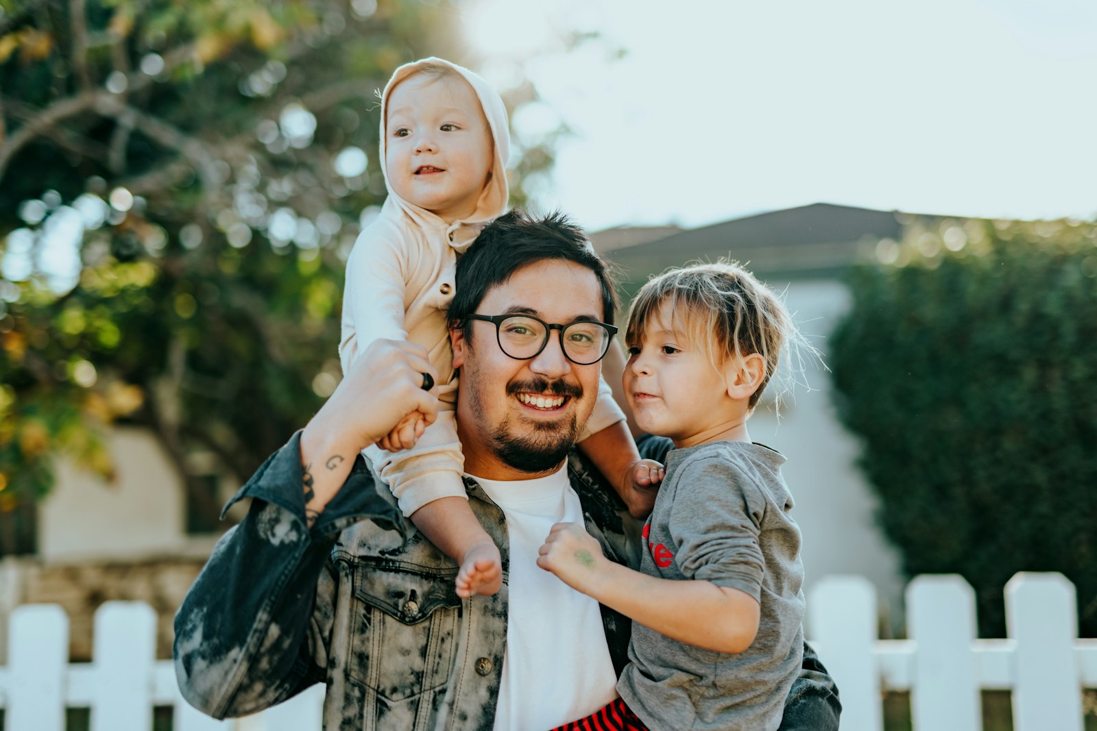 A father outdoors with his two young children